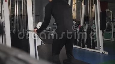 <strong>健身器</strong>材上英俊的健美运动员训练的后视图